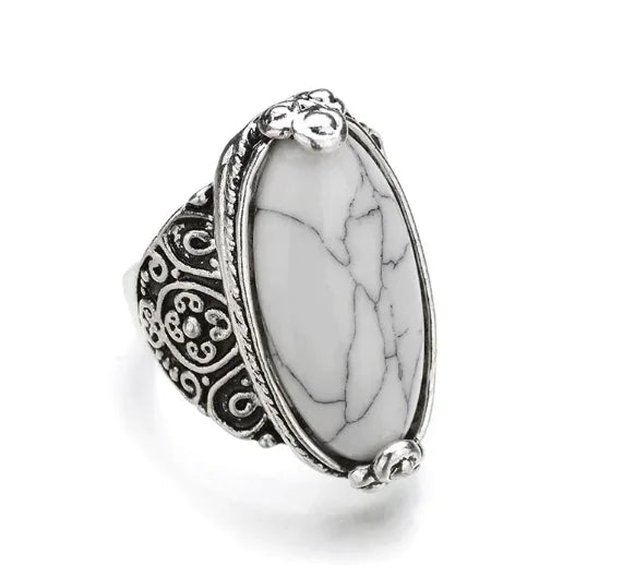 A ring with a large black stone set in a silver-colored mounting with intricate designs around the band.