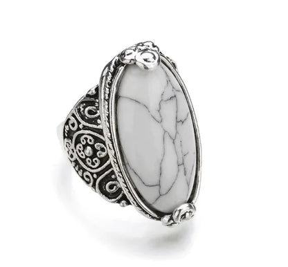 A ring with a large black stone set in a silver-colored mounting with intricate designs around the band.