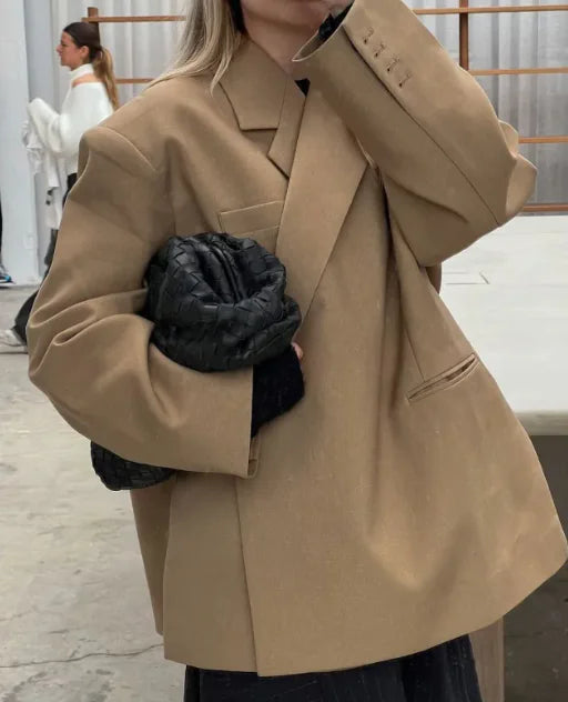 A woman sitting at a table wearing a long-sleeve black spandex jacket with a collared neckline.