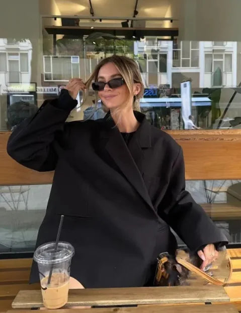 A woman sitting at a table wearing a long-sleeve black spandex jacket with a collared neckline.